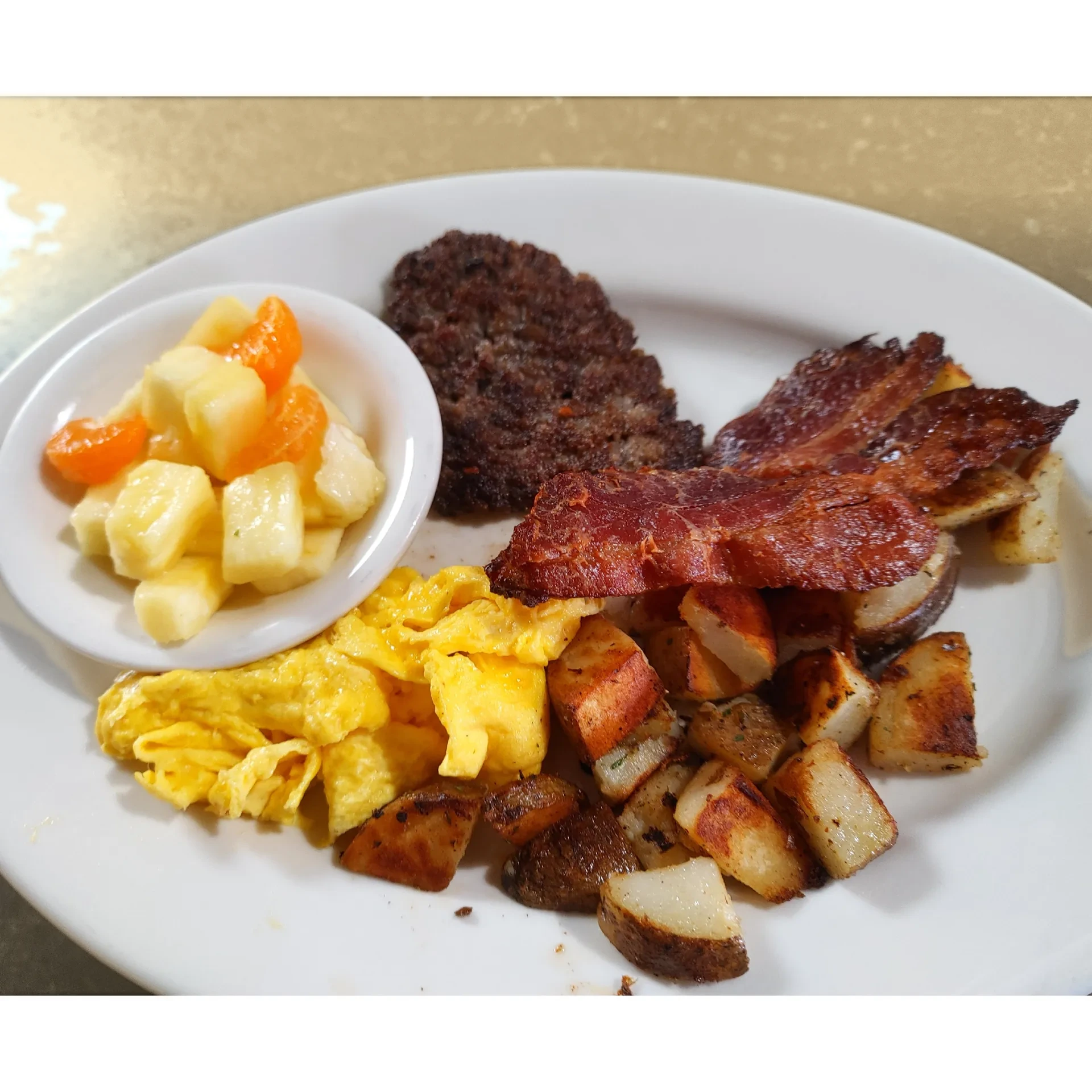 The Milo Sampler — two eggs, bacon, sausage, house potatoes, and fresh fruit